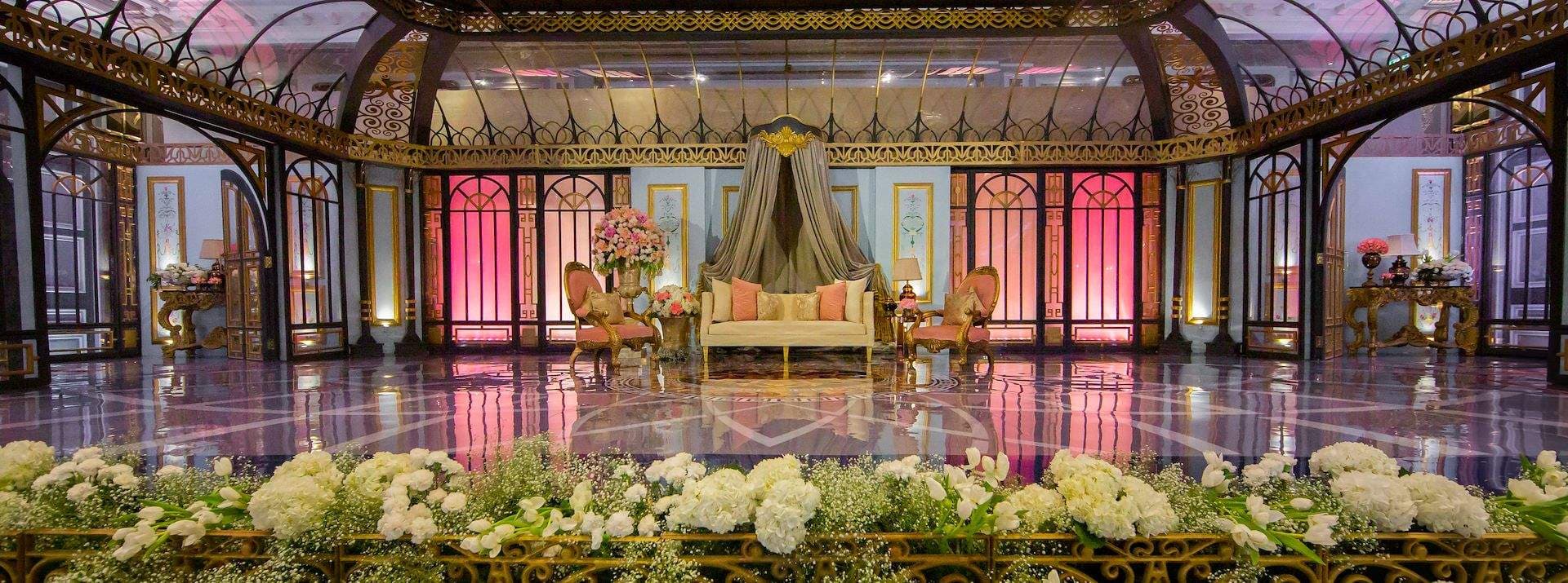 Ornate wedding stage with floral foreground and glass-house decor at Courtyard by Marriott, Ahmedabad