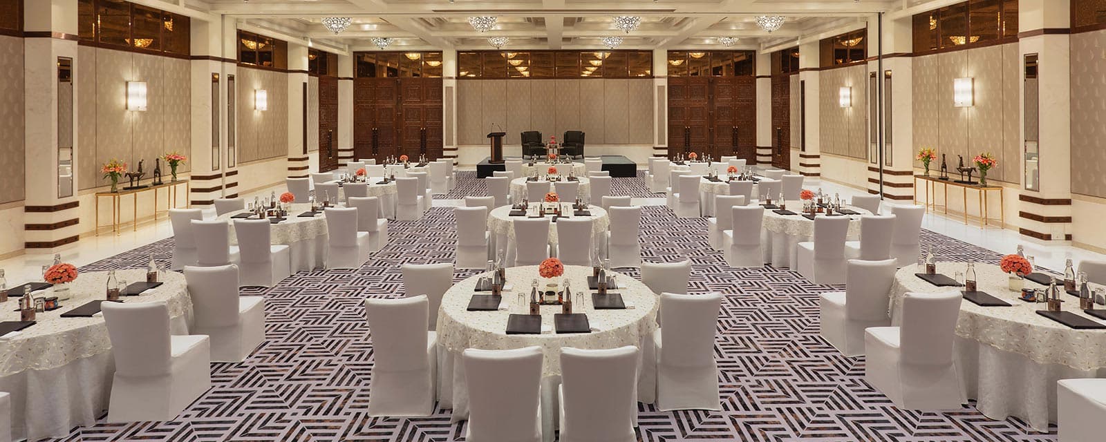 The pillarless banquet hall at ITC Narmada, Ahmedabad, set with round tables and chandeliers