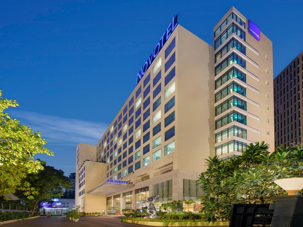 Exterior facade of Novotel Ahmedabad on SG Highway lit up at dusk