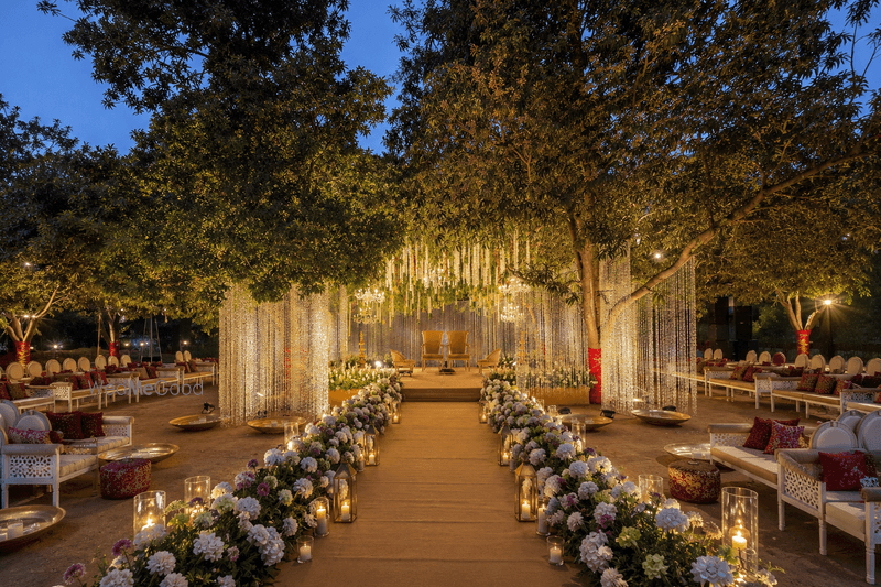 Outdoor wedding setup with string lights and a floral-lined aisle at Ruta Farm, Adalaj, Gandhinagar