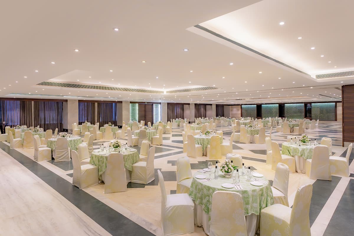 Banquet hall at The Grand Bhagwati (TGB), Ahmedabad, set with round tables in green and white linens